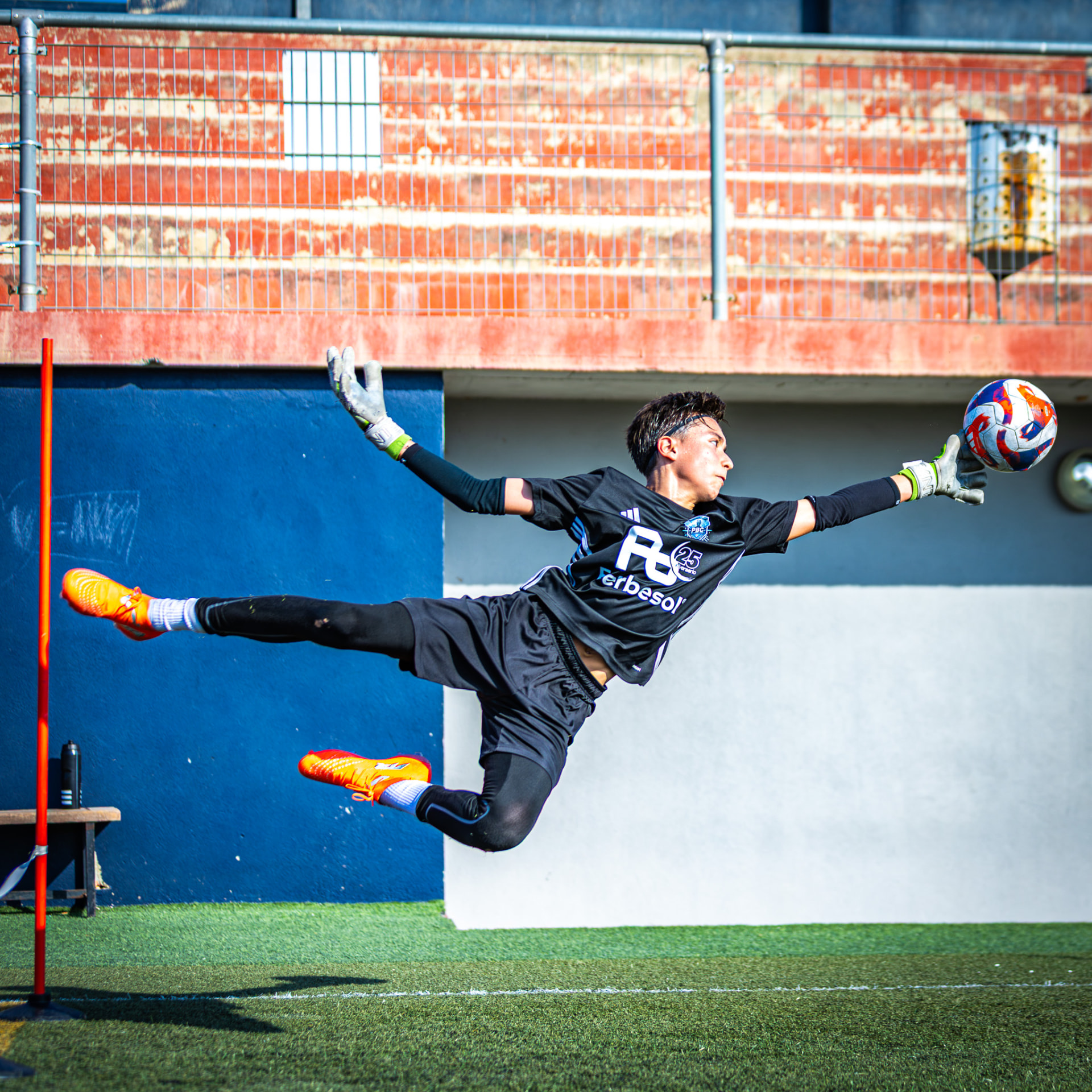 Portero joven en estirada aérea para atrapar el balón